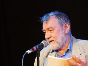 Middle-aged man leans in towards a microphone
